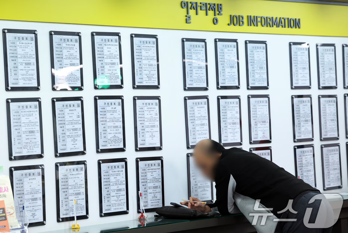 한 남성이 구인 정보가 게시된 일자리정보 벽면을 보며 메모를 하고 있다.