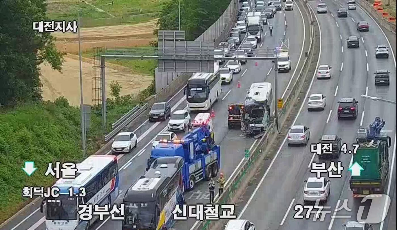 고속도로에서 버스와 차량이 사고를 일으켜 견인차, 구급차 등이 출동해 있는 모습. 주변에 교통체증이 발생했으며 도로 표지판과 방향 안내가 보인다.