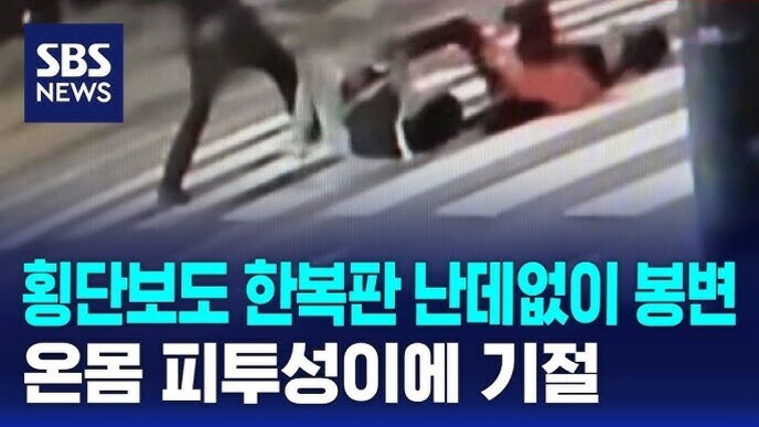 SBS 뉴스 로고와 함께 횡단보도에서 한 사람이 다른 사람을 넘어뜨리는 장면과 '횡단보도 한복판 난데없이 봉변 온몸 피투성이에 기절'이라는 자막이 있는 이미지