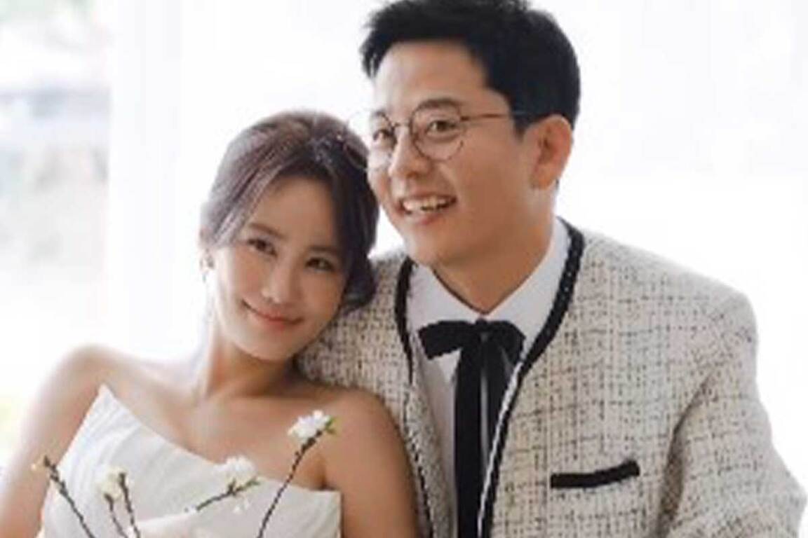 웨딩드레스를 입은 여성과 턱시도를 입은 남성이 나란히 앉아 미소 짓고 있는 모습