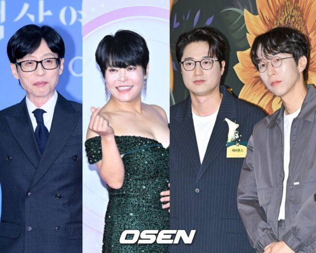 정장을 입은 남성 두 명과 드레스를 입고 손가락 하트를 하는 여성, 그리고 캐주얼한 옷차림의 남성이 나란히 서 있는 모습