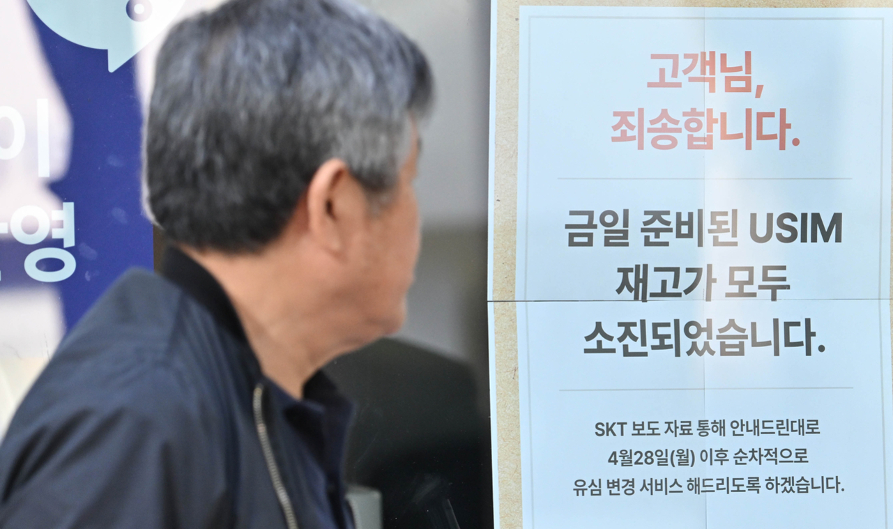 한 남성이 '고객님, 죄송합니다. 금일 준비된 USIM 재고가 모두 소진되었습니다.'라는 안내문을 바라보고 있다.