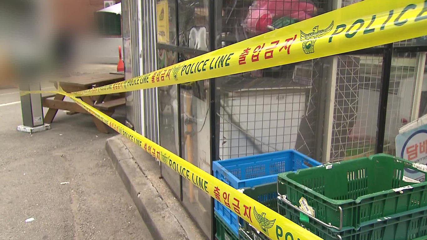 상점 앞에 경찰 통제선(출입금지)이 설치되어 있고, 플라스틱 바구니와 벤치가 보인다.