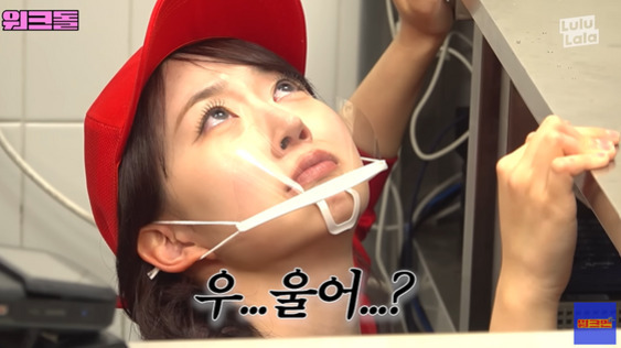 빨간 모자를 쓴 여성이 투명 마스크를 착용하고 위를 올려다보며 눈물을 참는 듯한 표정을 짓고 있다. 화면에는 '우...울어...?'라는 자막이 보인다.