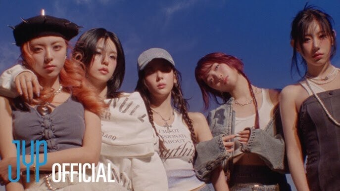 다섯 명의 젊은 여성들이 다양한 패션을 입고 야외에서 포즈를 취하고 있다. 왼쪽 하단에 'JYP OFFICIAL' 로고가 보인다.