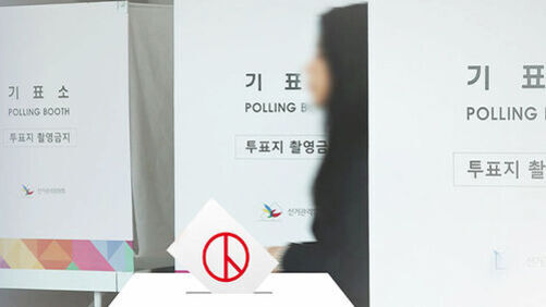 기표소 앞을 지나가는 사람과 '투표지 촬영금지' 문구가 적힌 안내문이 보인다.