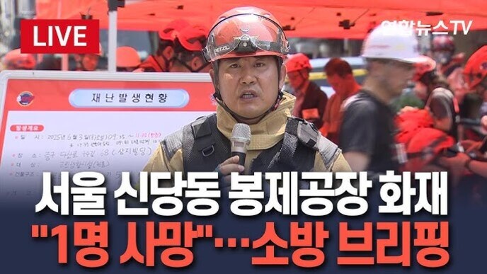 서울 신당동 봉제공장 화재 현장에서 소방관이 마이크를 들고 브리핑을 하고 있으며, 화면 하단에 '1명 사망'이라는 자막과 함께 사고 상황을 전하는 뉴스 방송 장면.
