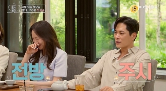 두 남녀가 테이블에 앉아 대화를 나누고 있으며, 한 명은 미소를 짓거나 웃고 있고 다른 한 명은 진지한 표정이다. 화면 좌측 상단에는 방송 정보와 KBS2 로고가 보인다.