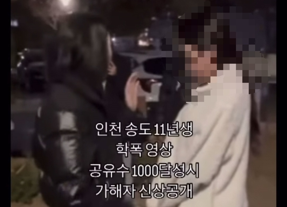밤에 야외에서 두 사람이 마주 서 있고, 한 사람은 검정색 패딩을 입고 있으며 다른 한 사람의 얼굴은 모자이크 처리되어 있다. 화면 중앙에는 '인천 송도 11년생 학폭 영상 공유수 1000달성시 가해자 신상공개'라는 문구가 적혀 있다.