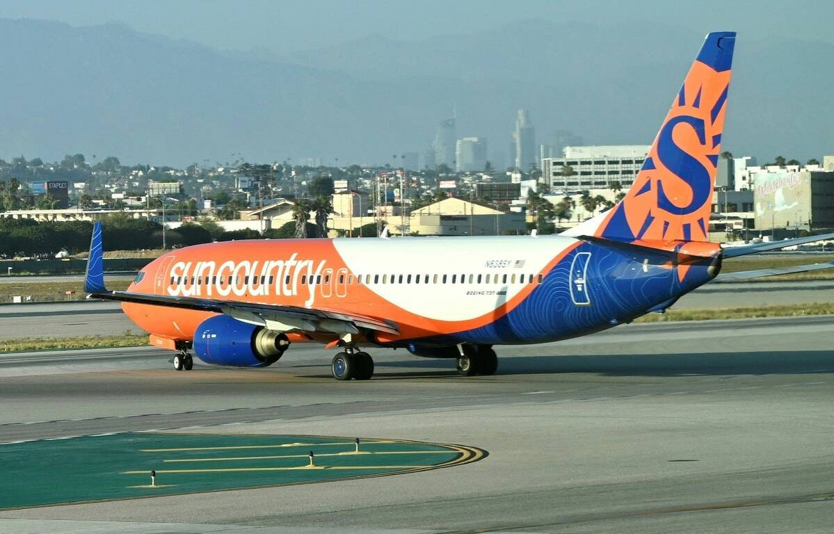 공항 활주로에 주황색과 파란색의 Sun Country Airlines 여객기가 서 있다.