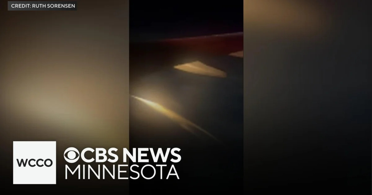비행기 창문 밖으로 어두운 하늘 아래 비행기 날개가 보이며, 화면 왼쪽 하단에 'WCCO CBS NEWS MINNESOTA' 로고가 있다.