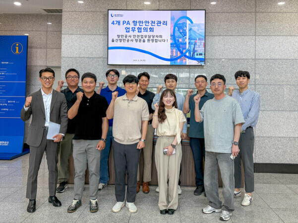 10명의 남성과 1명의 여성이 실내에서 모여 서서 카메라를 향해 주먹을 쥔 채 포즈를 취하고 있다. 뒤에는 '4개 PA 항만안전관리 업무협의회'라는 문구가 적힌 전광판이 보인다.