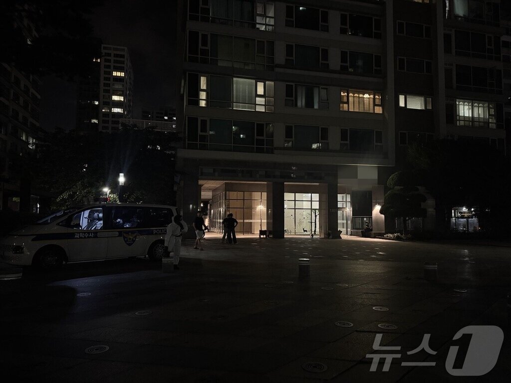 밤에 아파트 입구 앞에서 경찰 과학수사 차량과 관계자들이 출입하고 있는 모습