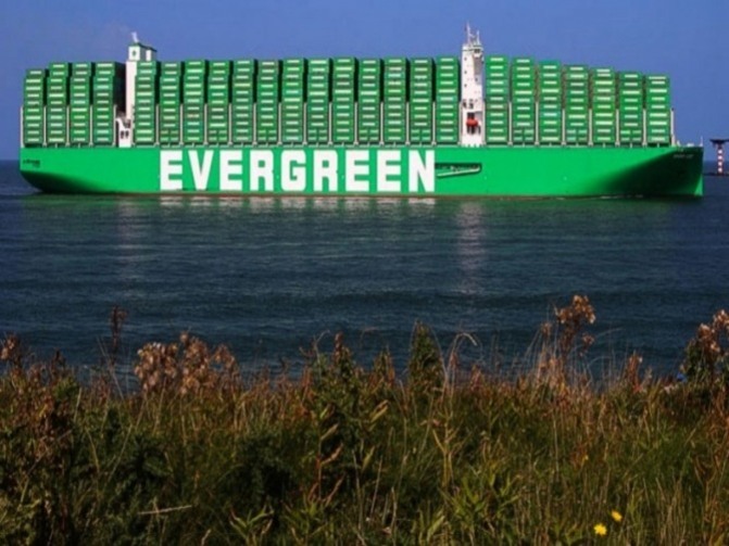 초록색 컨테이너로 가득한 대형 화물선 'EVERGREEN' 호가 바다 위를 항해하고 있다. 앞쪽에는 풀이 자라고 있다.