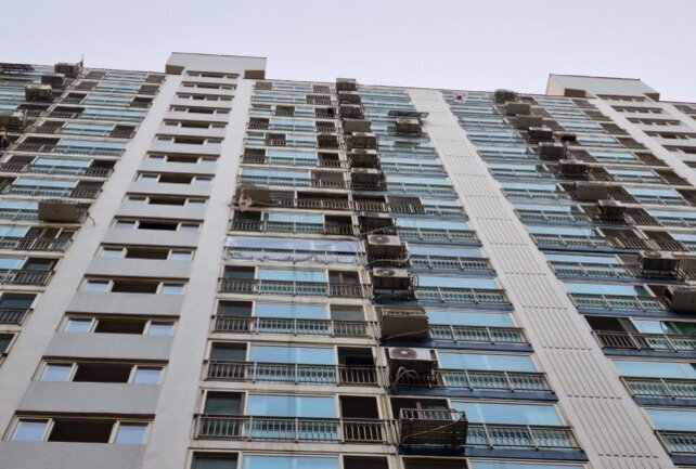 고층 아파트 외관을 아래에서 올려다본 모습, 각 세대에 에어컨 실외기가 설치되어 있음.