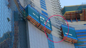 고층 건물 외벽에 설치된 안전 가림막 일부가 붕괴된 모습이 빨간 원으로 표시되어 있다.