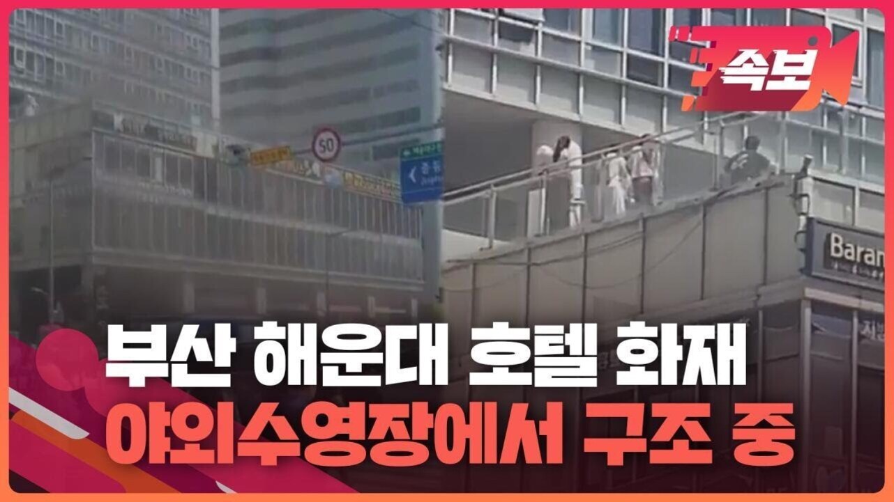 부산 해운대 호텔 건물 외벽과 야외 수영장에서 사람들이 구조되고 있는 모습, 화면 상단에는 '속보'라는 표시와 함께 하단에 '부산 해운대 호텔 화재 야외수영장에서 구조 중'이라는 자막이 있음.