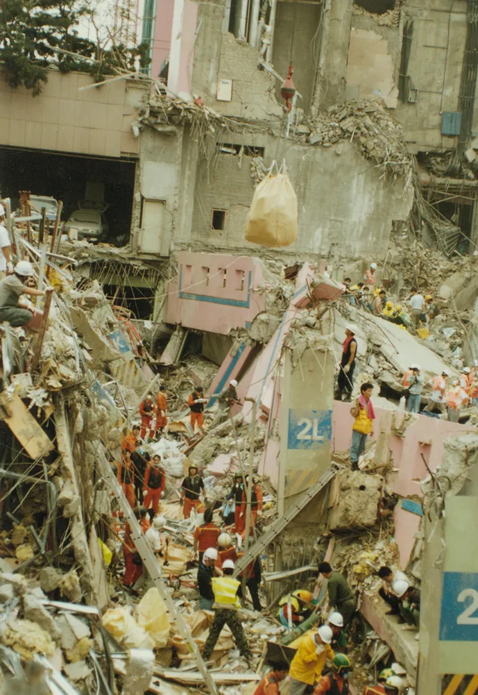 붕괴된 건물 잔해 위에서 구조대원들이 수색 및 구조 작업을 하고 있는 모습