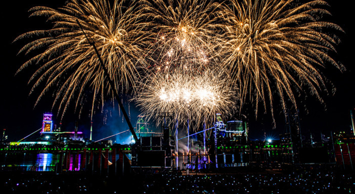 밤하늘에 밝고 화려하게 터지는 불꽃놀이와 조명이 비치는 도시 풍경