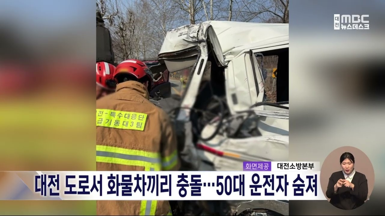 소방관들이 대전의 한 도로에서 화물차끼리 충돌한 사고 현장에서 구조 작업을 하고 있다. 화면 하단에는 '대전 도로서 화물차끼리 충돌…50대 운전자 숨져'라는 뉴스 자막이 보인다.