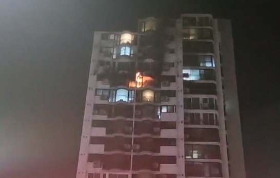 밤에 고층 아파트의 한 층에서 불이 나고 있는 모습