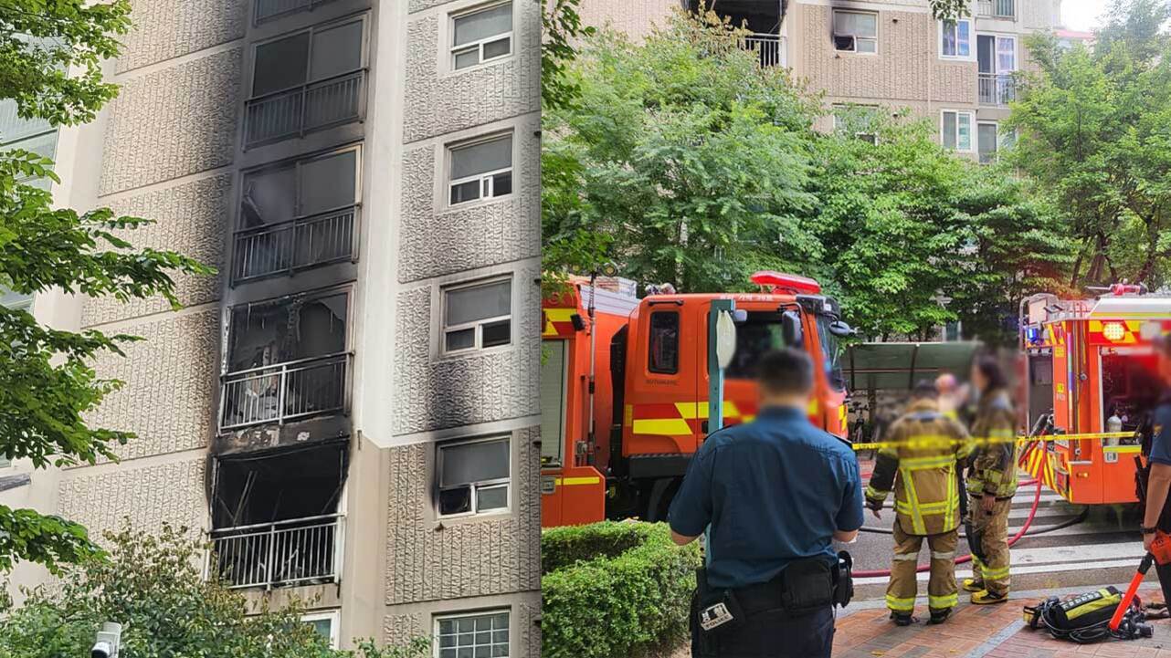 아파트 건물 외벽이 심하게 그을려 있고, 소방차와 경찰이 출동해 있는 현장에 소방관들과 경찰들이 모여 있다.