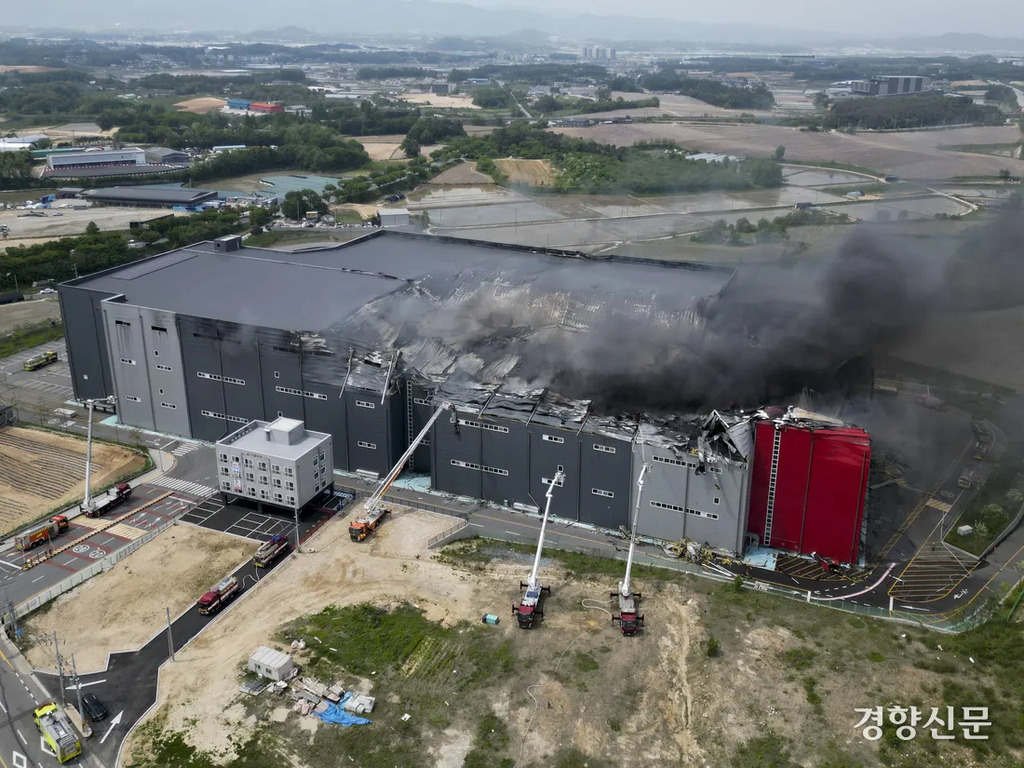 대형 건물에서 화재가 발생하여 지붕이 심하게 파손되고 검은 연기가 치솟고 있다. 소방차 여러 대가 출동해 진화 작업을 하고 있다.