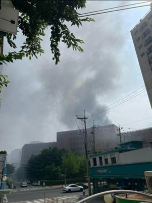 도심 건물에서 검은 연기가 크게 피어오르고 있는 화재 현장 모습