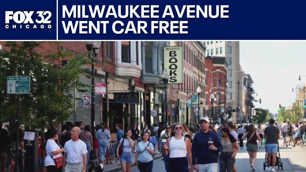 밀워키 애비뉴에서 차량이 없는 거리를 많은 사람들이 걷고 있으며, 상점과 나무가 보이고 거리 분위기가 활기차다. 화면 상단에는 'MILWAUKEE AVENUE WENT CAR FREE'라는 뉴스 자막이 있다.