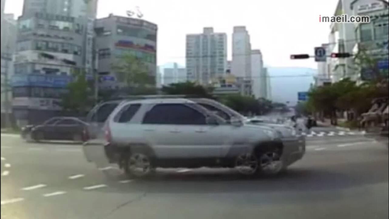 도시 교차로에서 여러 차량이 움직이는 모습이 겹쳐 보이며, 배경에는 고층 건물과 신호등이 있다.