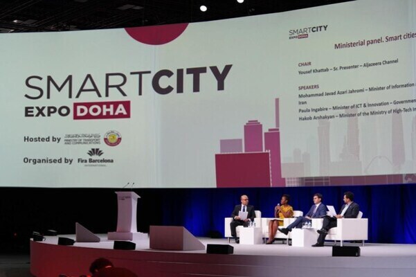 대형 스크린에 'SMART CITY EXPO DOHA'라는 글자가 보이고, 네 명의 연사가 무대 위 소파에 앉아 토론을 진행하고 있다.