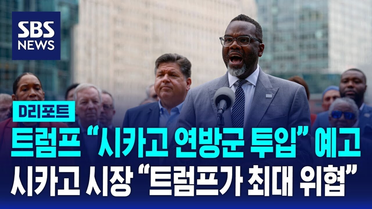 SBS NEWS 로고와 함께 한 남성이 마이크 앞에서 연설하고 있으며, 배경에는 여러 사람들이 서 있다. 화면 하단에 '트럼프 시카고 연방군 투입 예고 시카고 시장 트럼프가 최대 위협'이라는 자막이 있다.